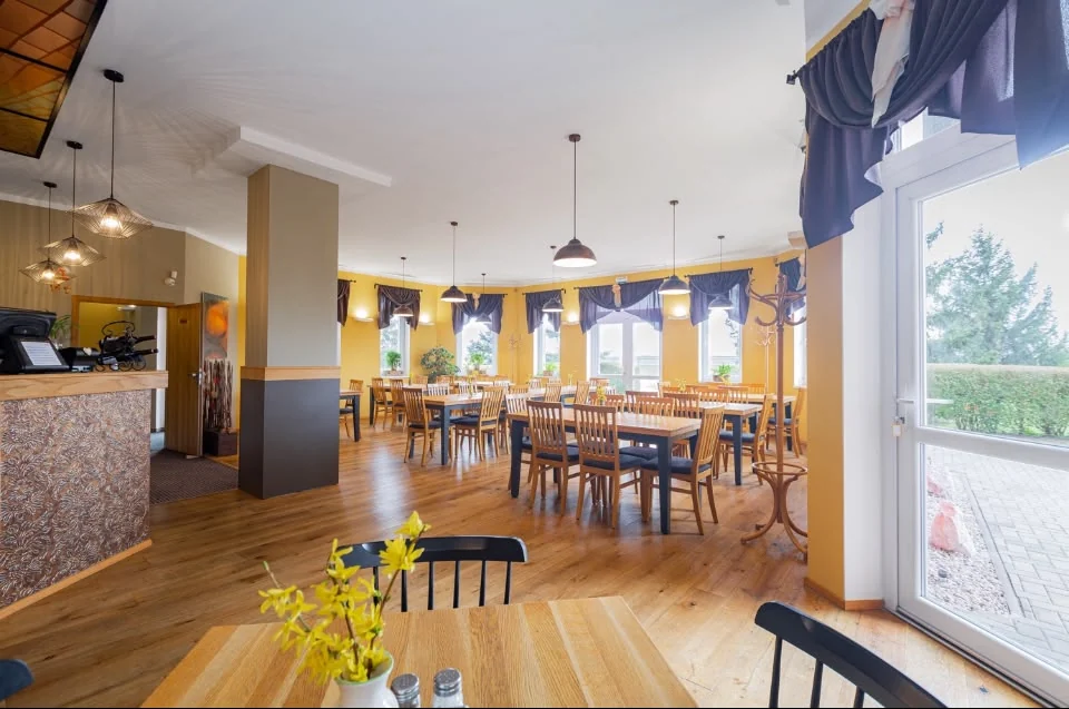 Světlý prostor restaurace se stoly a výhledem do zahrady